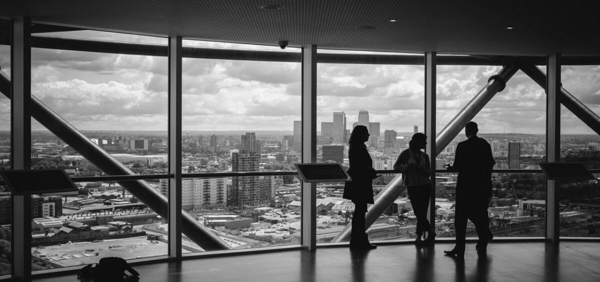 Black and white image of people viewing the city inside of large building
