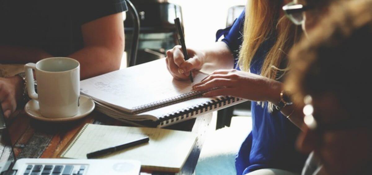 Woman writing down notes during group meeting