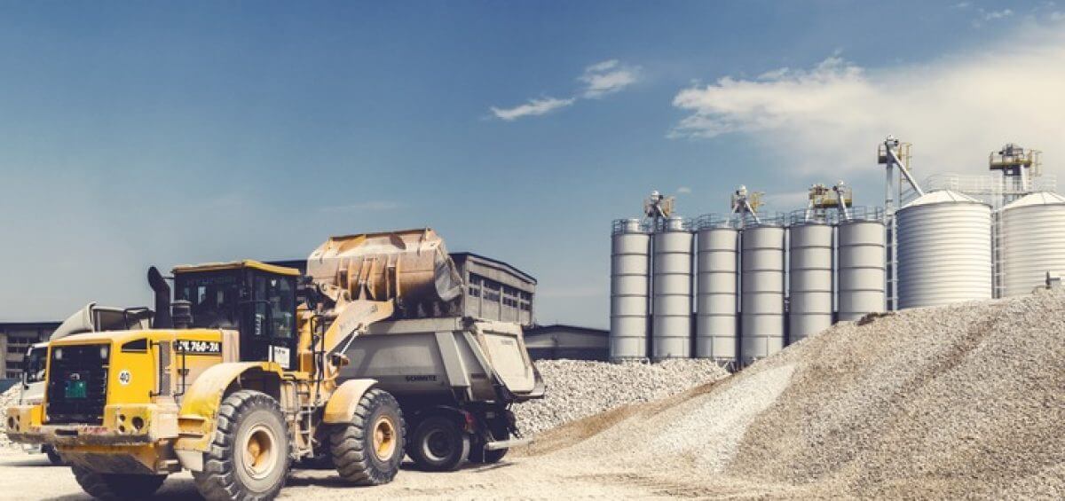 Yellow heavy equipment truck working on site with Schmitz truck