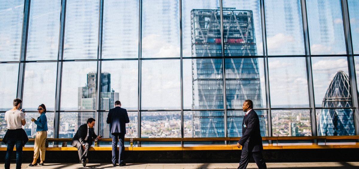 A businessman walking through a skyscraper building with view of city