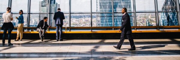 A businessman walking through a skyscraper building with view of city