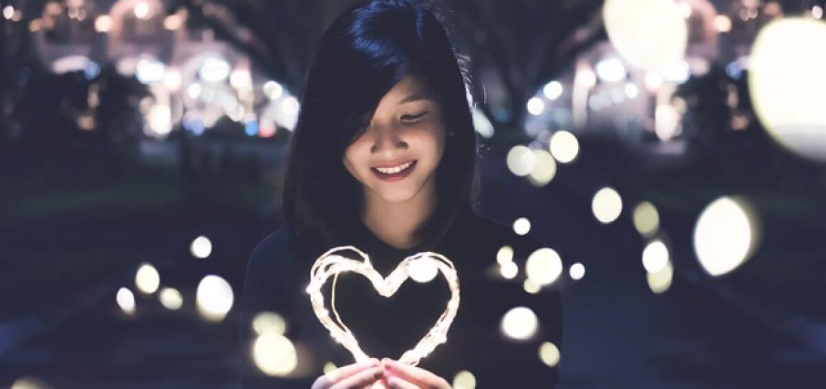 Young Asian woman holding string lights in the shape of a heart for the Perth international arts festival