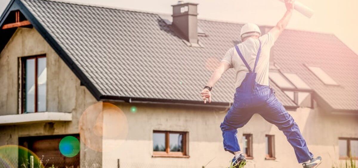 Builder jumping for joy with blueprint plans in his hand