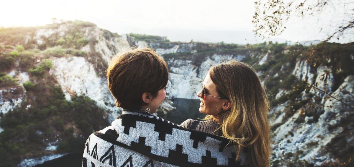 A same sex couple sitting on mountains