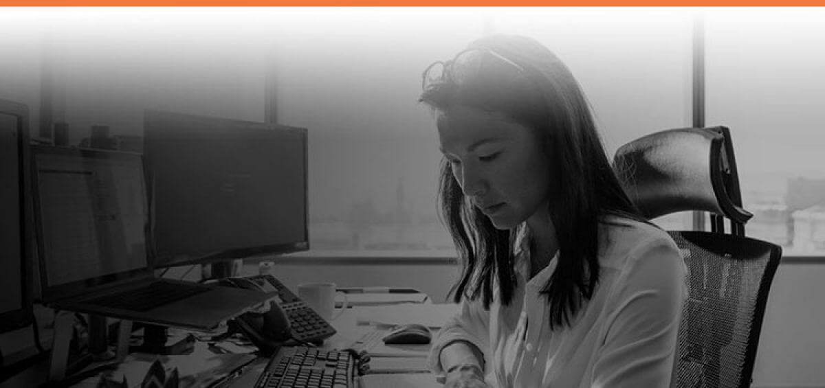 Woman doing work at her desk with Interstaff orange top border for Complex Migration service