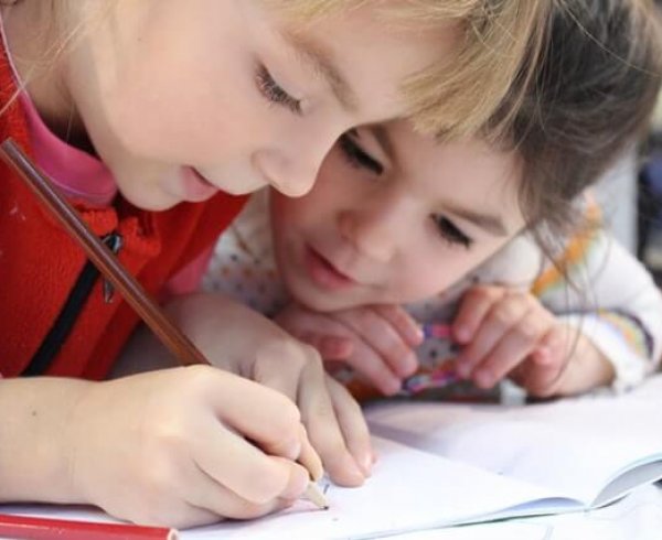 Two young girls doing a pencil drawing at school