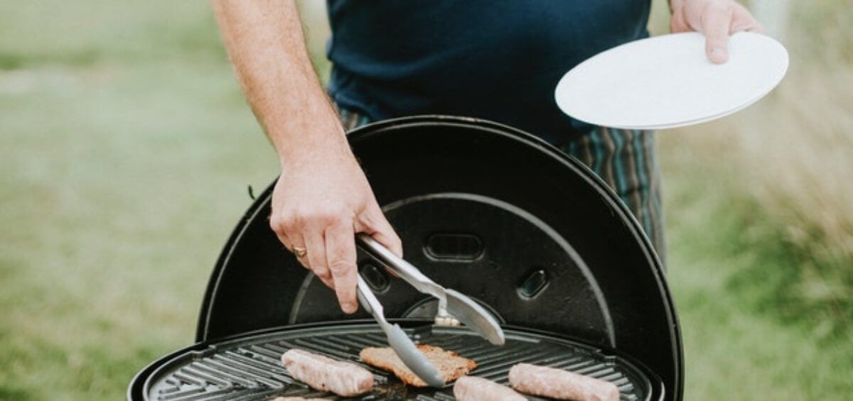 Australia man cooking democracy sausage a BBQ on the grill