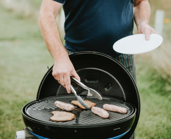 Australia man cooking democracy sausage a BBQ on the grill