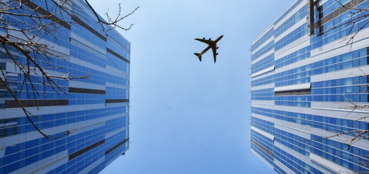 A plane flying over buildings for Visa Entry Conditions 8504