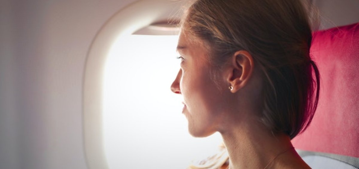 Woman looking outside of airplane as she reflects on temporary visa holder changes announced by the Government
