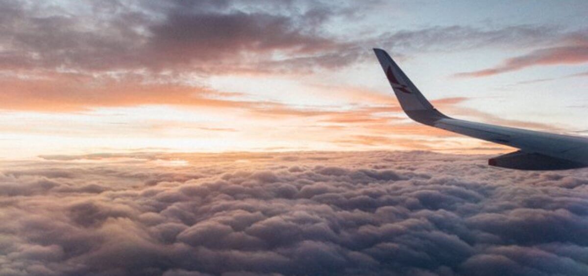 A plane in the air with clouds as background for Australia's economic outlook immigration post by Interstaff